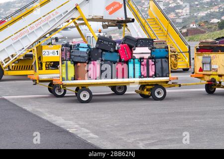 Un chariot à bagages chargé de valises et de sacs de voyage en attente de transfert au terminal de l'aéroport pour la collecte. Banque D'Images