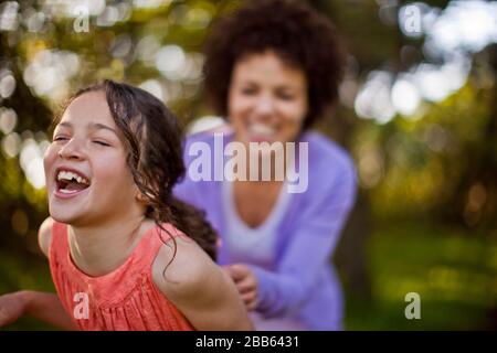 Rire jeune fille en étant tickled par sa mère dans une forêt. Banque D'Images