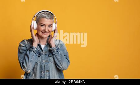 Amateur de musique. Portrait d'une femme mûre souriante dans un casque sans fil Banque D'Images