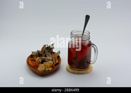 Gros plan d'un verre de thé au gingembre et de diverses herbes. Banque D'Images