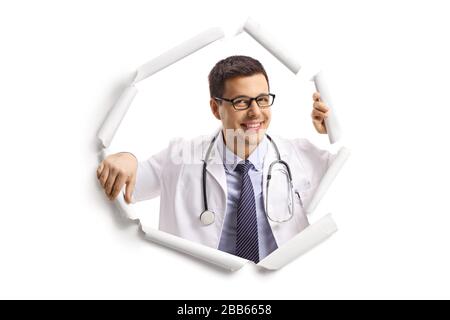 Jeune médecin souriant et regardant par un trou de papier blanc Banque D'Images