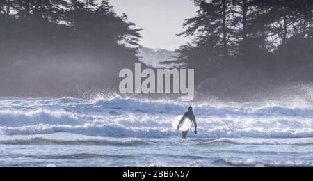 Silhouette d'un surfeur Marche dans le surf, Pacific Rim National Park, Colombie-Britannique, Canada Banque D'Images