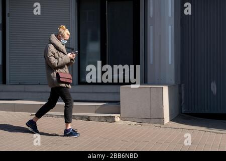 Kiev, Ukraine, 27 mars 2020, femme dans un masque facial protecteur marchant le long de la rue Banque D'Images
