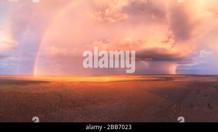 Coucher de soleil orageux avec double arc-en-ciel, nuages de cumulus et cellules de pluie sur un lac sec en Australie Banque D'Images