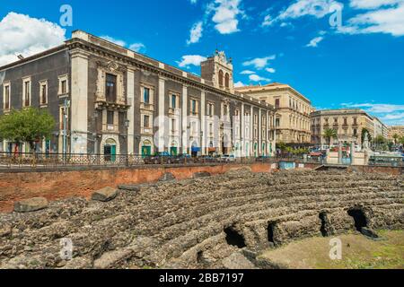 Catane - avril 2019, Sicile, Italie: Amphithéâtre romain de Catane, ruines d'un ancien théâtre. Vue sur le palais de Tezzano (Palazzo Tezzano) Banque D'Images