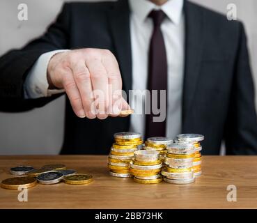 Concept de mi-section d'un homme d'affaires avec une grande quantité de pièces de comptage en espèces en piles pour ajouter des bénéfices et des actifs d'entreprise. Banque D'Images