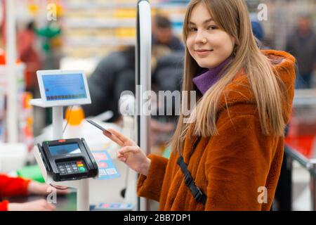 La jeune femme avec une carte de crédit paie pour les achats au comptoir de caisse du magasin Banque D'Images