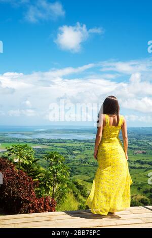 Belle fille en robe jaune regarde la nature Banque D'Images