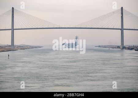 Le porte-avions de classe Nimitz de la marine américaine USS Dwight D. Eisenhower traverse sous le pont de paix de Moubarak lorsqu'il transite le canal de Suez le 9 mars 2020 à El Qantara, en Egypte. Banque D'Images