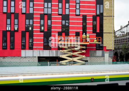 Constructeurs sur une plate-forme de monteur de cerises ou de boum au chantier de construction du bâtiment rouge de Horgan's Quay, à Cork, en Irlande, en novembre 2019 Banque D'Images