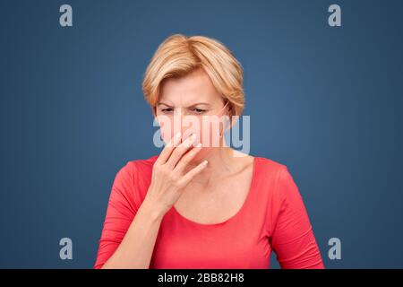 Concept de coronavirus. Femme blonde isolée sur bleu dans le masque facial toux concecrned Banque D'Images