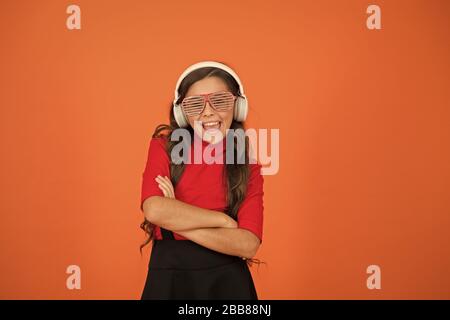 Accessoire de fête. Fille avec lunettes arrière-plan orange. Événement et divertissement. Fille de fête. Amuse-toi bien. Liste de lecture pour la fête. Concept de musique. Enfant porter des lunettes. Magasin de mode de lunettes. Piste froide. Banque D'Images