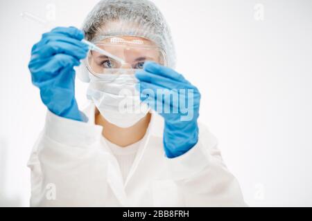 jeune assistant dans l'usure de protection faisant le test de coronavirus avec un réactif spécial Banque D'Images