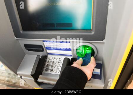 La main de l'homme insère la carte dans le distributeur automatique de billets au printemps. Finances, voyages, carte de crédit. Style de vie. Banque D'Images