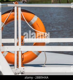 Photo d'un rail de garde sur un bateau avec un garde-vie orange attaché à lui. Banque D'Images