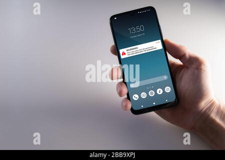 Notification d'avertissement de violation de quarantaine s'affiche sur un smartphone tenu par une main masculine. Conseils pour rester en quarantaine à domicile pour arrêter la contagion. Pandémie, santé Banque D'Images