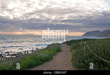 Femme marchant sur un sentier sur des falaises au-dessus de l'océan Pacifique à Malibu sur la côte sud de la Californie. Banque D'Images