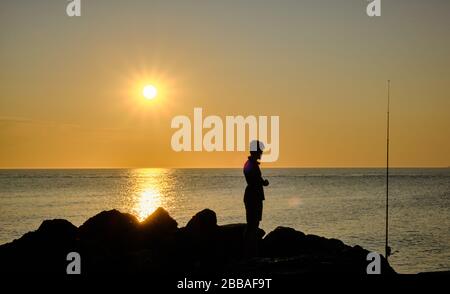 Vue sur une ombre de pêcheur sur les rochers de la côte de Punta Ballena sur la baie de Solanas, océan atlantique, Maldonado, Uruguay Banque D'Images