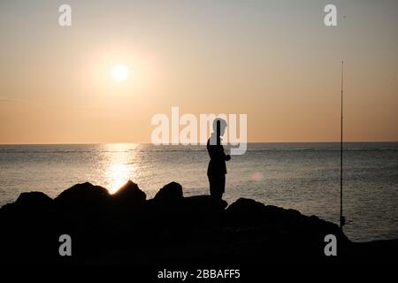 Vue sur une ombre de pêcheur sur les rochers de la côte de Punta Ballena sur la baie de Solanas, océan atlantique, Maldonado, Uruguay Banque D'Images