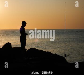 Vue sur une ombre de pêcheur sur les rochers de la côte de Punta Ballena sur la baie de Solanas, océan atlantique, Maldonado, Uruguay Banque D'Images