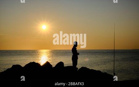 Vue sur une ombre de pêcheur sur les rochers de la côte de Punta Ballena sur la baie de Solanas, océan atlantique, Maldonado, Uruguay Banque D'Images