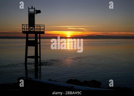 Coucher de soleil sur le détroit de Garry point de Géorgie. Coucher de soleil dans le détroit de Géorgie derrière l'aide à la navigation dans le parc Garry point, Steveston. Banque D'Images