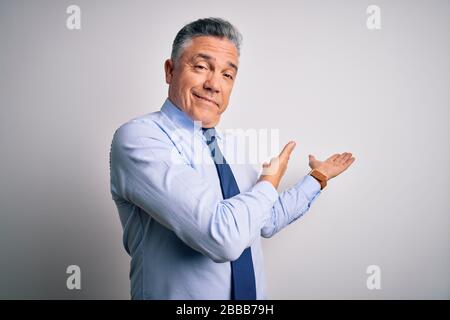 Homme d'affaires à poil gris avec une jolie chemise et une cravate à l'âge moyen pour entrer dans le sourire naturel avec une main ouverte Banque D'Images