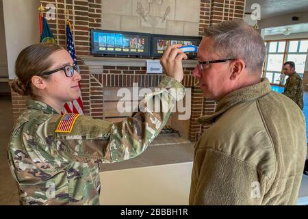 Sgt. Kate Cole, une medic du 209ème Régiment (Institut régional de formation) fait un contrôle de la température pour le major général Daryl Bohac, Nebraska adjudant général, alors qu'il entre dans le Memorial Hall pour une cérémonie de mise en service de candidat officier le 20 mars 2020, au Camp Ashland Training site, Nebraska. La cérémonie de mise en service a été ajustée pour s'assurer que les lignes directrices actuelles des centres de contrôle et de prévention des maladies ont été suivies afin d'empêcher la propagation de la COVID-19. (Photo de la Garde nationale du Nebraska par le Sgt. Lisa Crawford) Banque D'Images