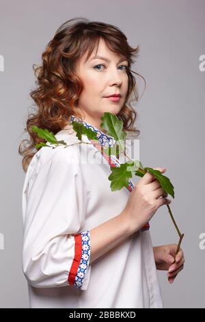 portrait complet de la femme slave à tête rouge avec branche de chêne en vêtements russes traditionnels Banque D'Images
