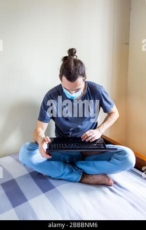 Concept de séjour à la maison. Quarantaine en cas de pandémie de coronavirus. Homme d'affaires travaillant à domicile, porter un masque de protection. Travail à distance, apprentissage grâce à Banque D'Images