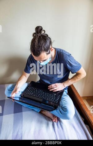 Concept de séjour à la maison. Quarantaine en cas de pandémie de coronavirus. Homme d'affaires travaillant à domicile, porter un masque de protection. Travail à distance, apprentissage grâce à Banque D'Images