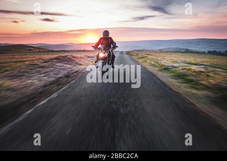 Balade en moto à travers la campagne pittoresque au beau lever du soleil - flou dynamique de mouvement. Banque D'Images