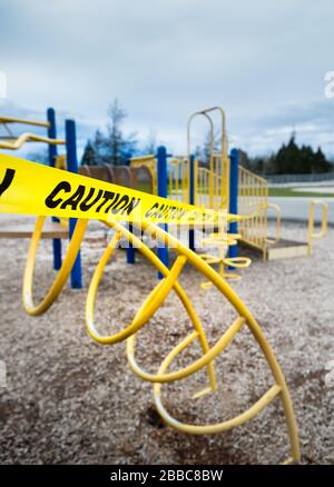 Ruban de mise en garde jaune entourant l'appareil d'escalade dans un terrain de jeux public fermé pendant la pandémie de Coronavirus Covid-19 Banque D'Images