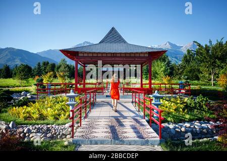 Femme en robe orange avec hat aller à la Pagode jardin japonais Banque D'Images