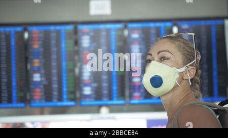 Femme caucasienne à l'aéroport de Suvarnabhumi avec masque médical protecteur. Carte d'information de vol. Coronavirus sars-cov-2 covid-19. Banque D'Images