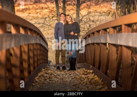 Adolescent fille et garçon debout sur le pont et souriant pendant l'heure d'or. Banque D'Images