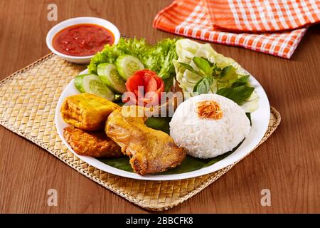 Formule de riz au poulet indonésien composée de riz, poulet frit, tofu frit, tempeh frit, légumes frais et sauce Chili Banque D'Images