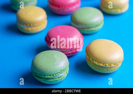 Dessert macarons colorés, fond bleu Banque D'Images