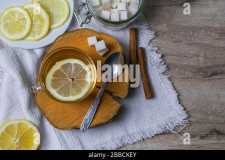 Tasse transparente en verre avec porte-thé à la menthe sur un support en bois, à côté d'un bol à sucre avec des cubes de sucre, du citron en tranches et une cuillère Banque D'Images