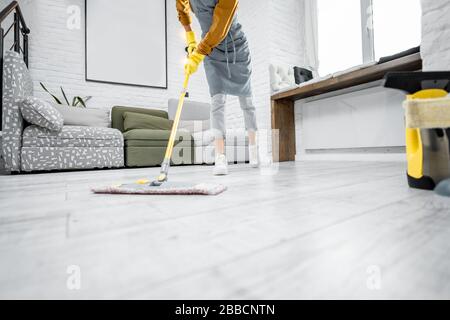 Femme se laver l'inondation avec un balai à franges dans le salon de l'appartement moderne, vue courte sans visage Banque D'Images