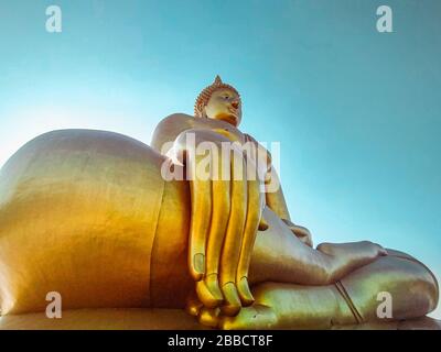 Gros plan de la grande statue de Bouddha avec le ciel bleu à Wat Tha Muang Thaïlande. Les statues de Bouddha d'or les plus emblématiques Banque D'Images