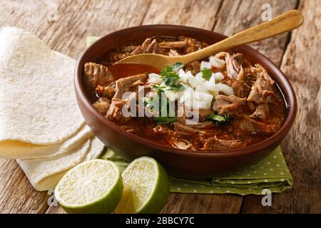 Service de Birria de Res chaud servi avec de la chaux et de la tortilla closeup dans un bol sur la table. Horizontal Banque D'Images