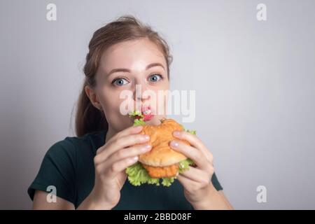 Jeune fille caucasienne souriante tenant manger du hamburger de poulet Banque D'Images