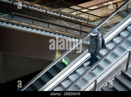 31 mars 2020, Berlin: Un homme avec un masque facial est debout sur un escalator dans la gare centrale de Berlin. Afin de ralentir la propagation du virus corona, la vie publique reste sévèrement restreinte. Photo: Kay Nietfeld/dpa Banque D'Images