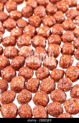 Gros plan de boules de chocolat dans le lait. Petit déjeuner rapide pour les enfants. Fond des boules de maïs. Format vertical. Mise au point sélective. Banque D'Images