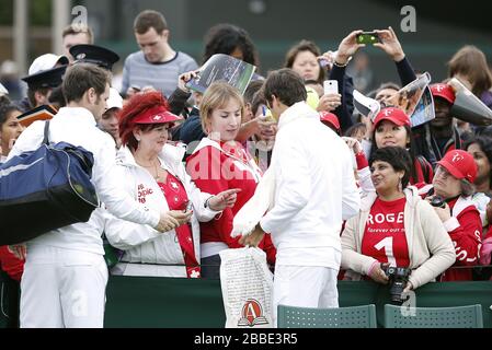 Roger Federer, Suisse, signe des autographes pour les fans en attente au cours de la première journée des championnats de Wimbledon au All England Lawn tennis and Croquet Club, Wimbledon. Banque D'Images