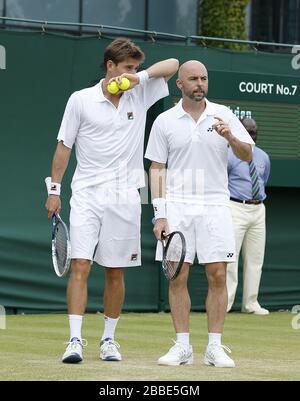 Les grands Britanniques Jamie Delgado (à droite) et l'Australias Matthew Ebden (à gauche) discutent de tactiques contre le Lleyton Hewitt australien et le Mark Knowles de Bahama au cours du quatrième jour des championnats de Wimbledon au All England Lawn tennis and Croquet Club, Wimbledon. Banque D'Images