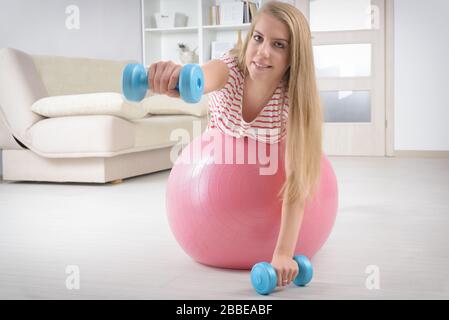 Belle jeune femme avec ballon de gym et haltères en exercice. Banque D'Images