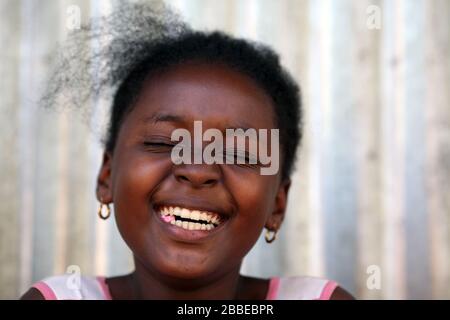 Une jeune fille malgache riant avec ses yeux fermés tout en mâchant de la gomme. Nosy Be, Madagascar. Banque D'Images