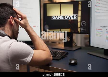 Homme en colère avec des lunettes après la perte de hir sur le jeu de tir en ligne. Jouez pour un homme compétitif. Banque D'Images